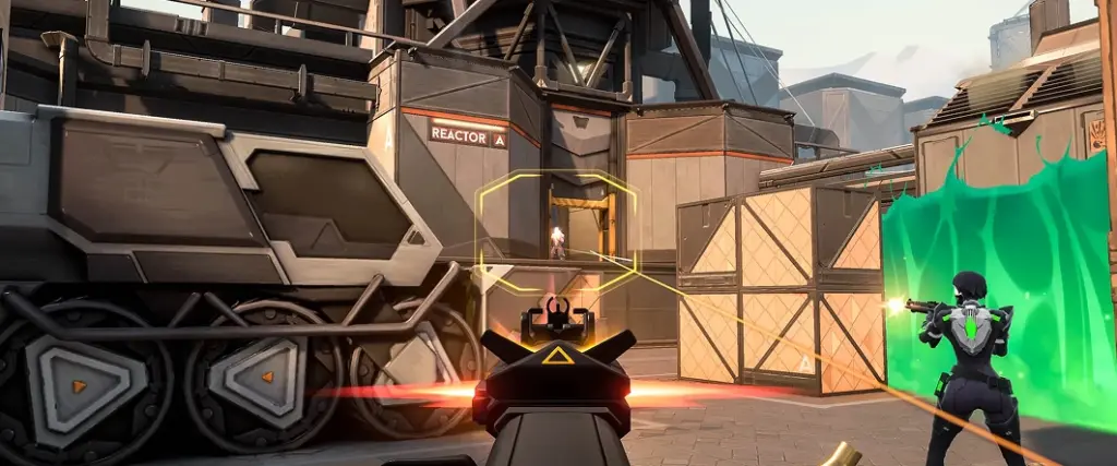 Scena z gry FPS, w której gracz celuje w wieżę oznaczoną jako „Reaktor A”. Obok stoi inna postać, otoczona neonowo zieloną barierą.